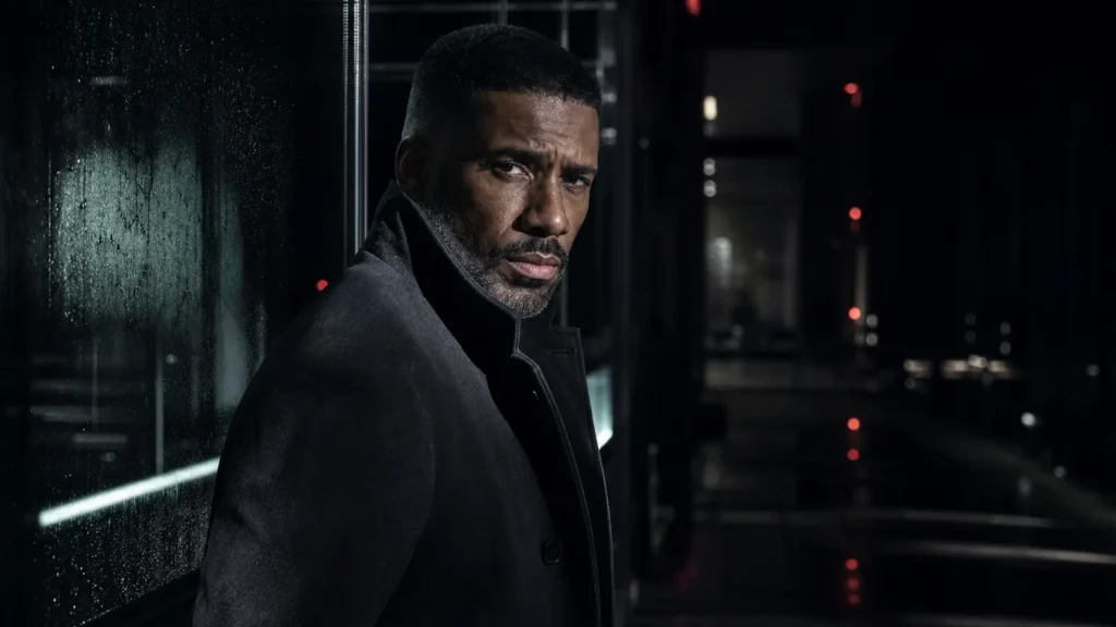 Man in a dark overcoat under cold strip lighting at night, looking straight at the camera. (AI-generated image)